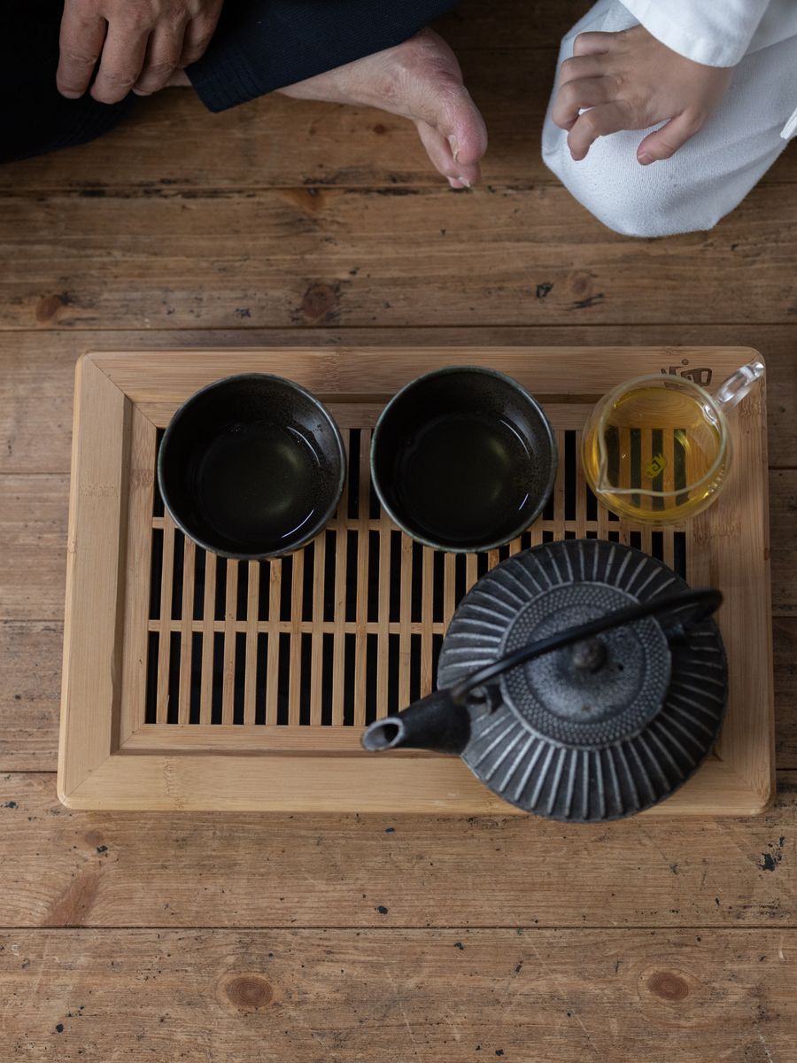 Théière en fonte et tasses sur un plateau en bois